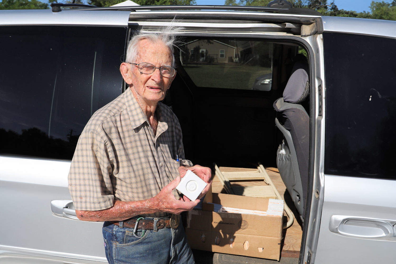 Don M. holding a rosette corner block in front of his van.