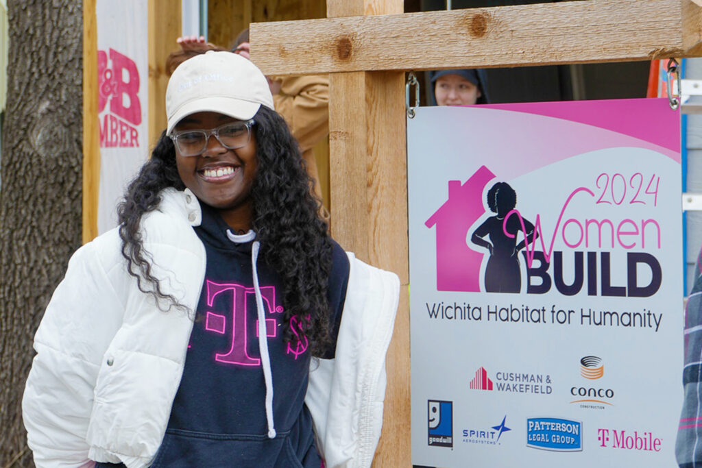 Family partner Indaka standing next to the Women Build yard sign.