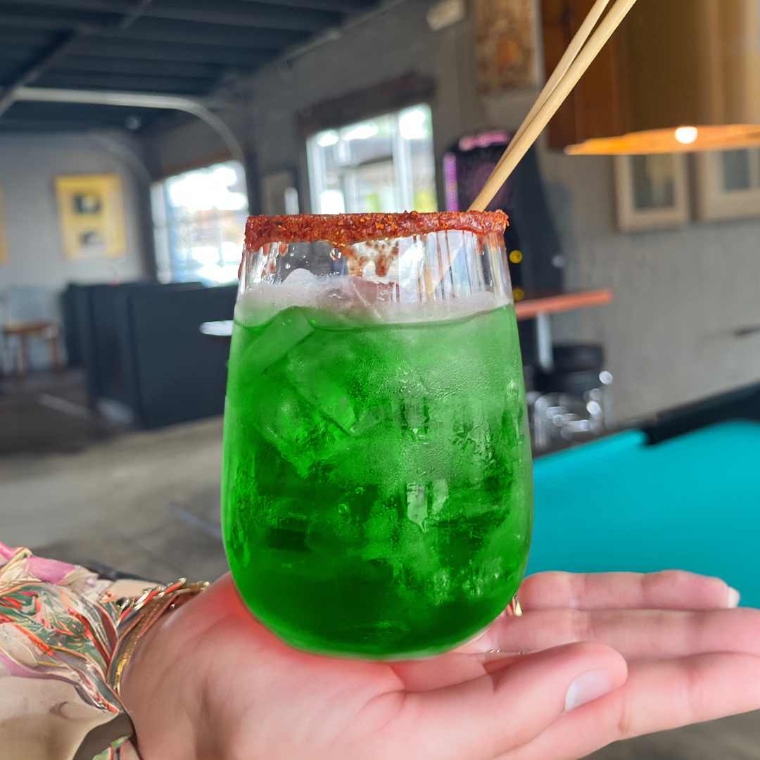 A red margarita drink on a person's hand.