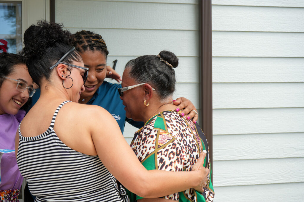 Family partner Lovetta in tears and surrounded by other family members and Habitat staff.