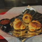 A tray of garlic knots with dipping sauce.