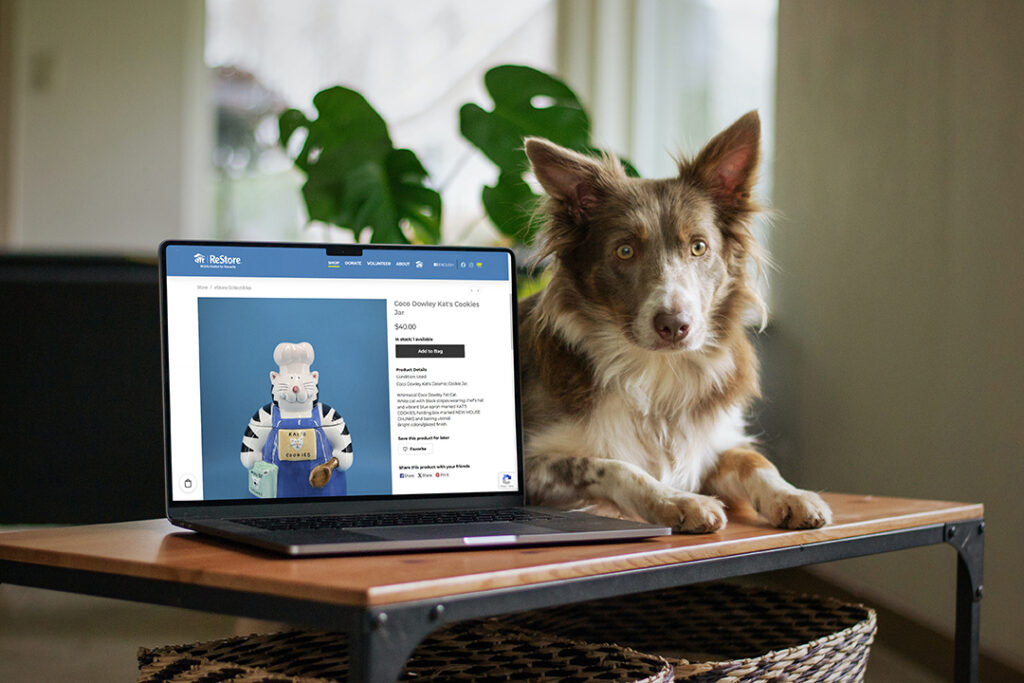 A laptop with ReStore eStore's shopping window open with a dog sitting next to it.