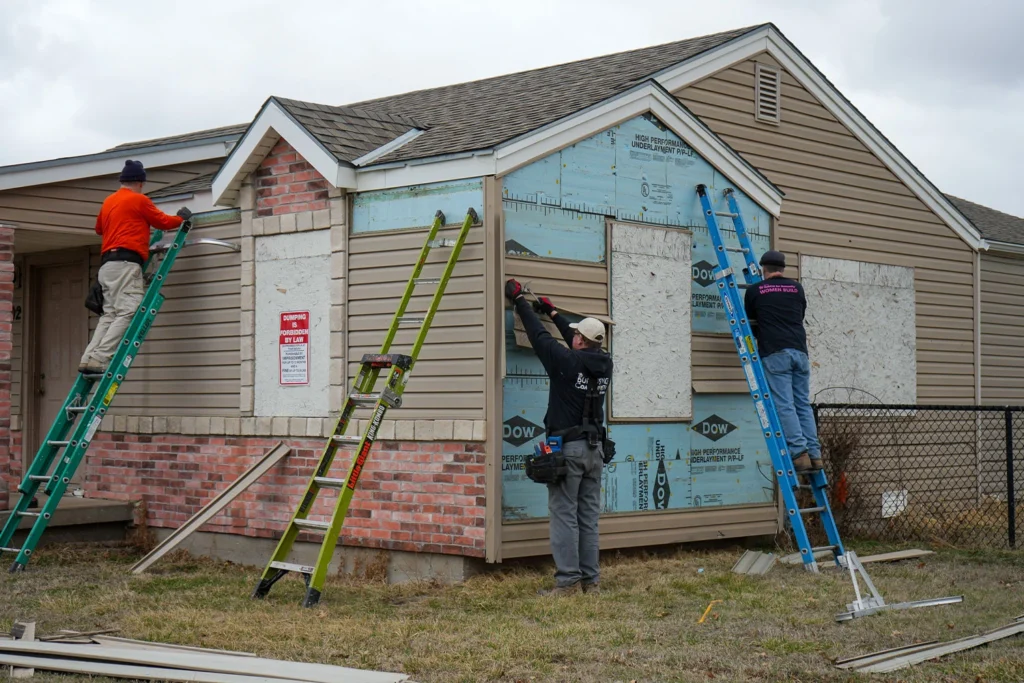 Core volunteers taking siding off a house.