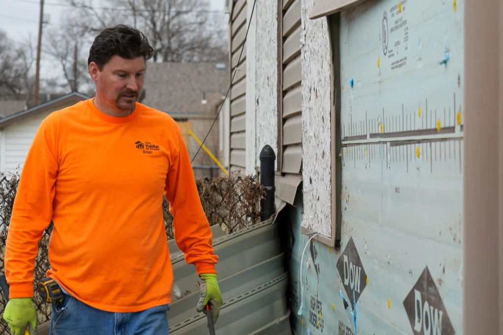 A construction staff taking siding off the wall.