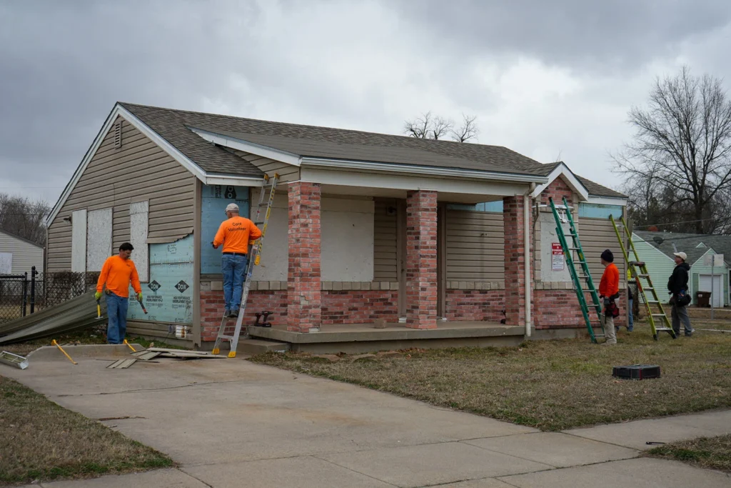 Core volunteers and staff taking siding off a house.