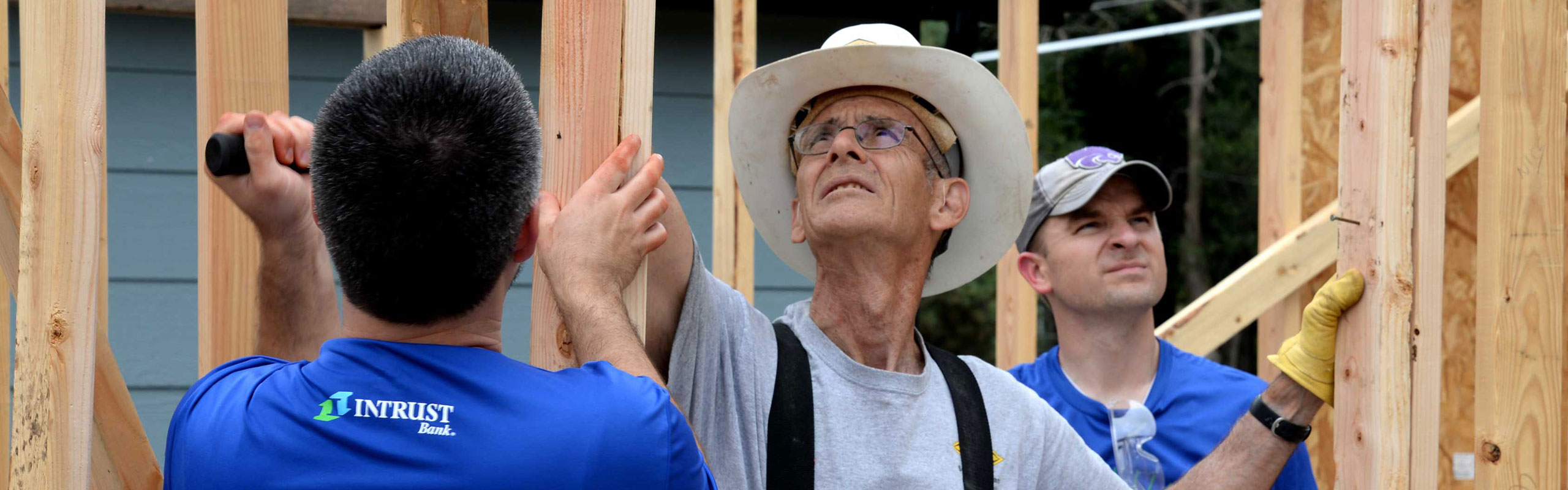 Construction volunteers helping raise up a wall.