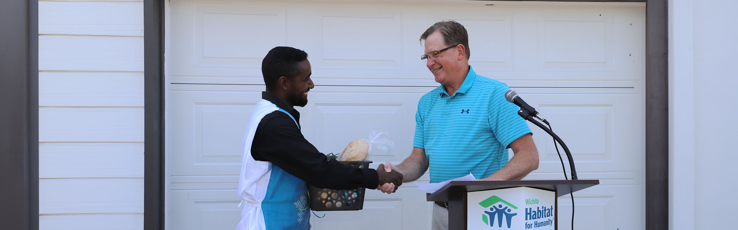 Mark Herbert shaking hands with a homebuyer at a home dedication ceremony.