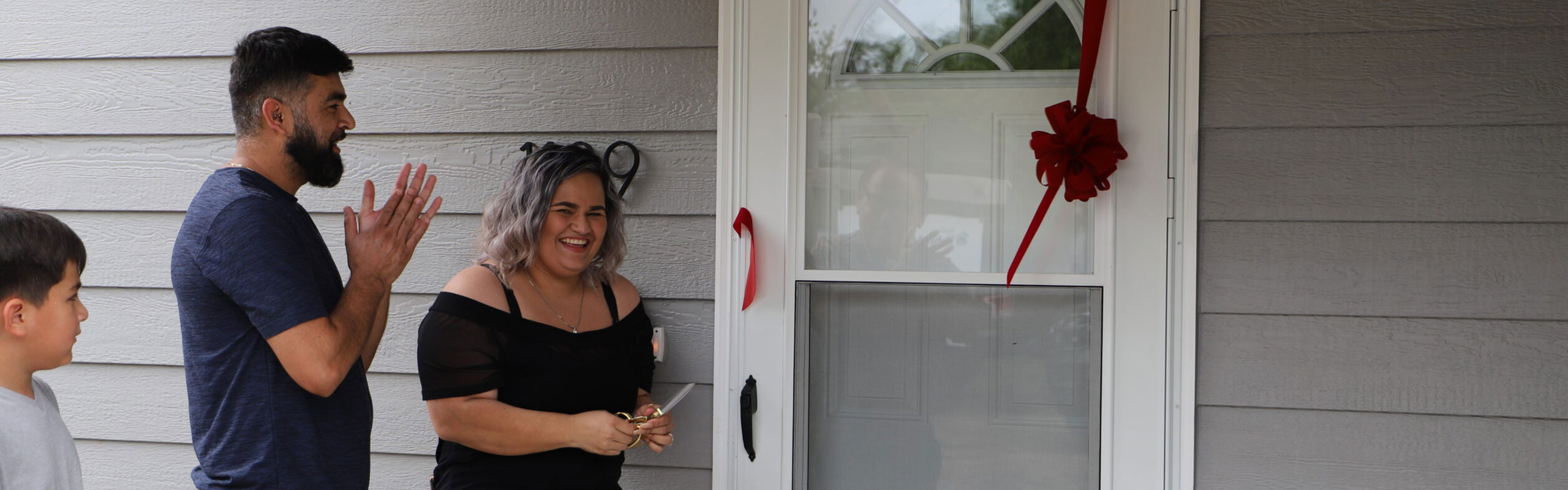 Homeowner cutting a ribbon off of a door.