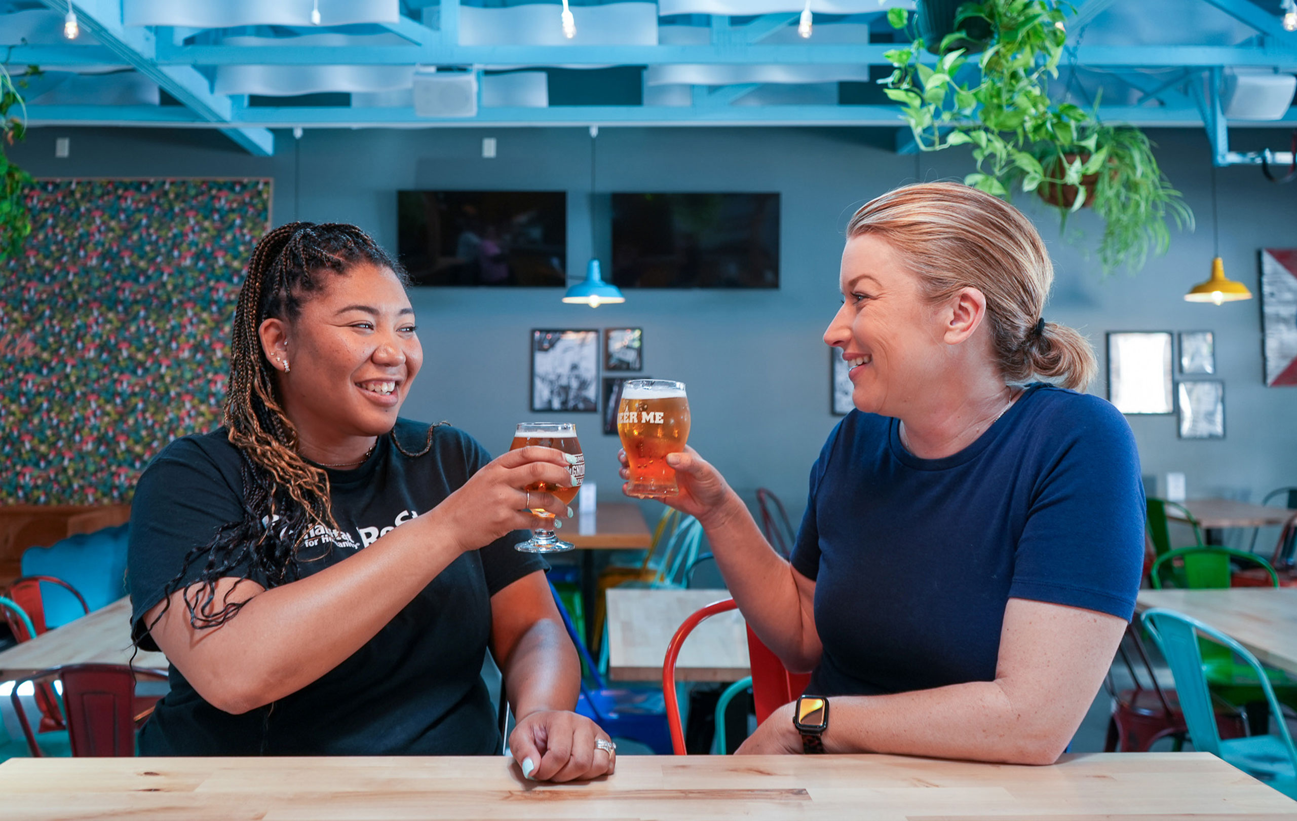 Two women clinking their glass of beer together.