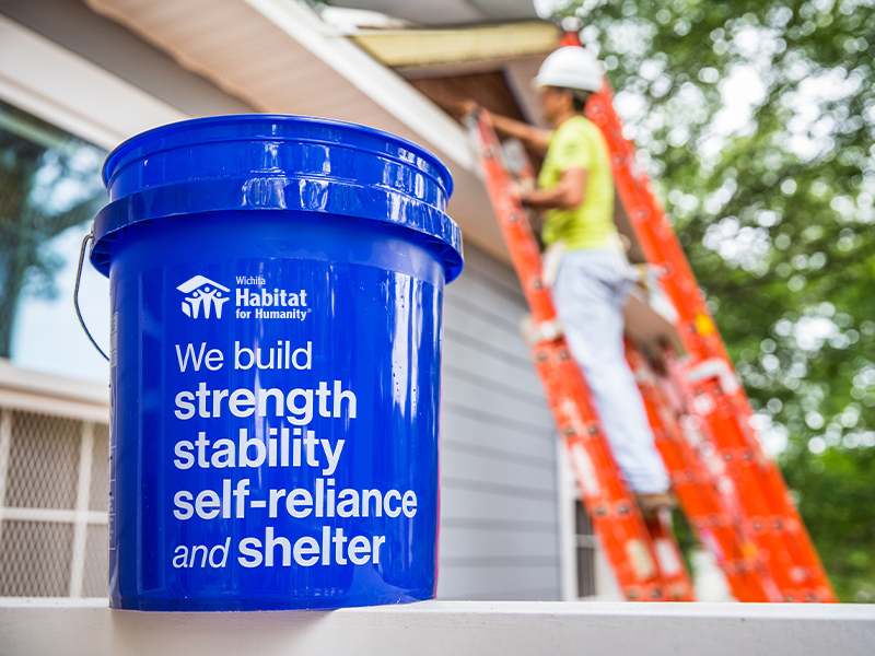 A blue bucket stating Habitat for Humanity's motto.