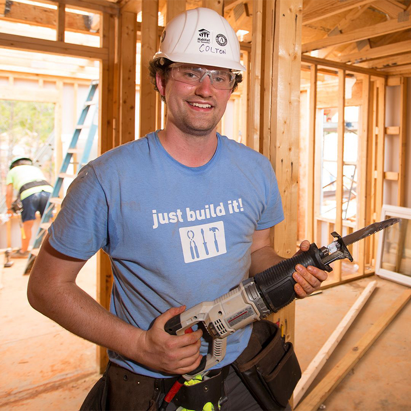 Male volunteer posing and holding a power tool.