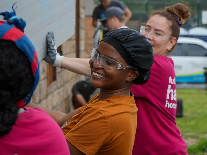 A family partner holding up siding with other volunteers.