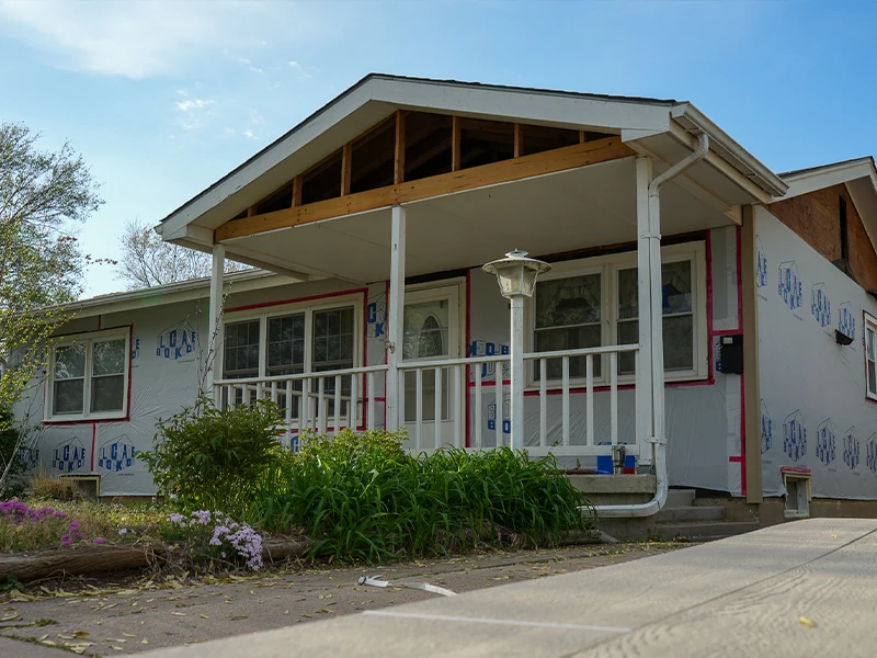 A house with plastic wrapped around the home in preparation for a siding repair.