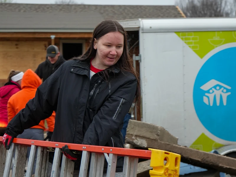 A volunteer carrying a ladder.