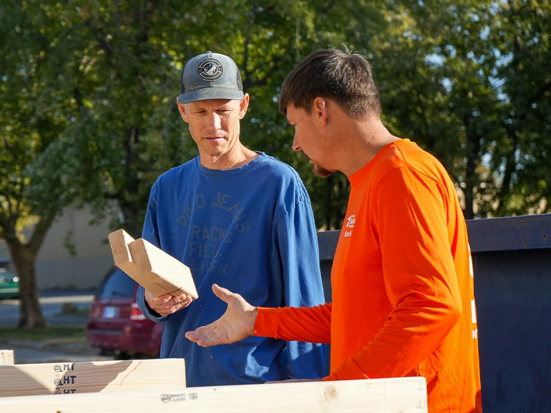 A volunteer handing over wood blocks to a construction member.