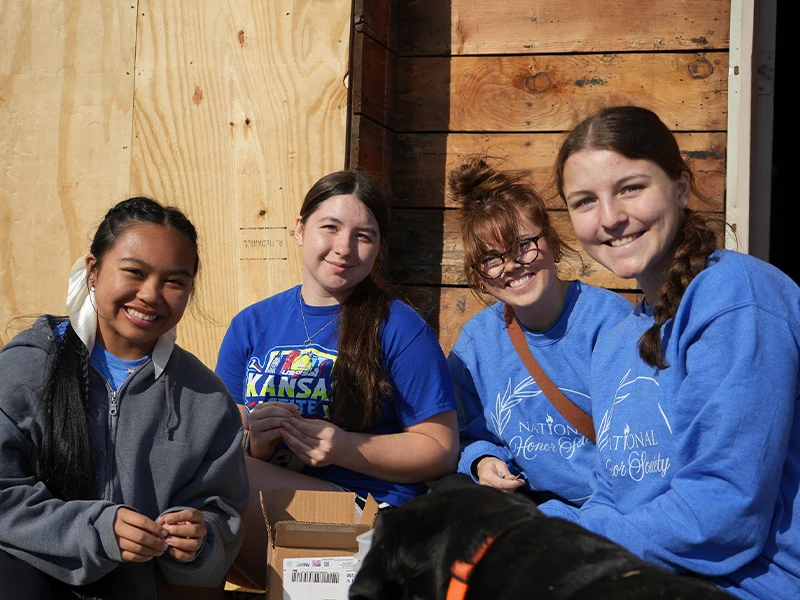High school volunteers smiling together and sorting nails.