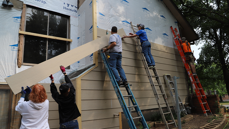 Volunteers putting new siding on an existing home.