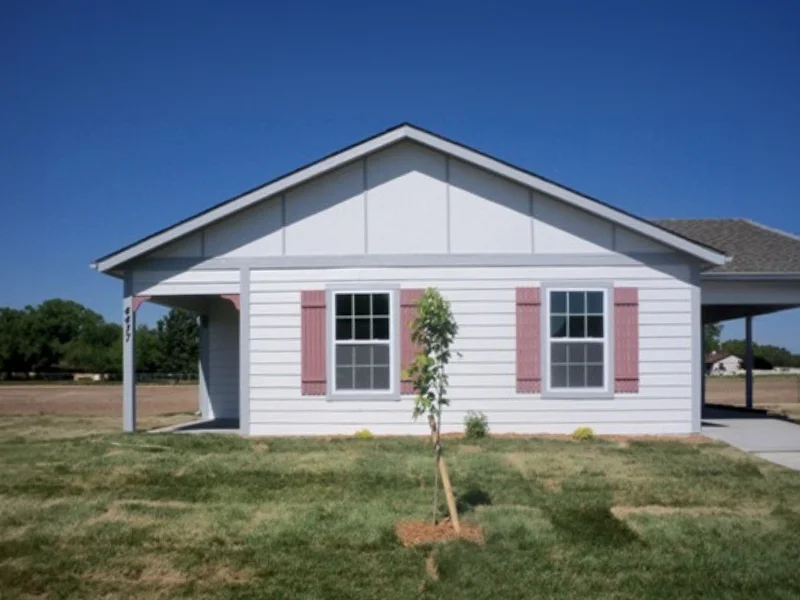 A small, single-story white house with a carport.