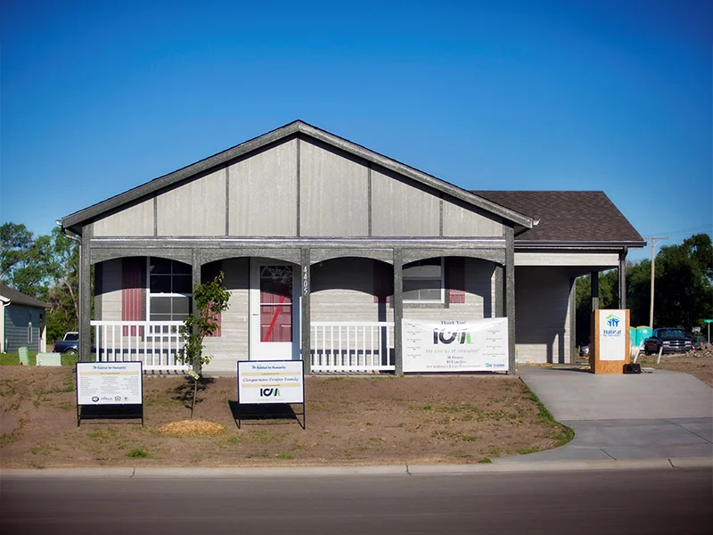 A small, single-story, gray house with a carport.
