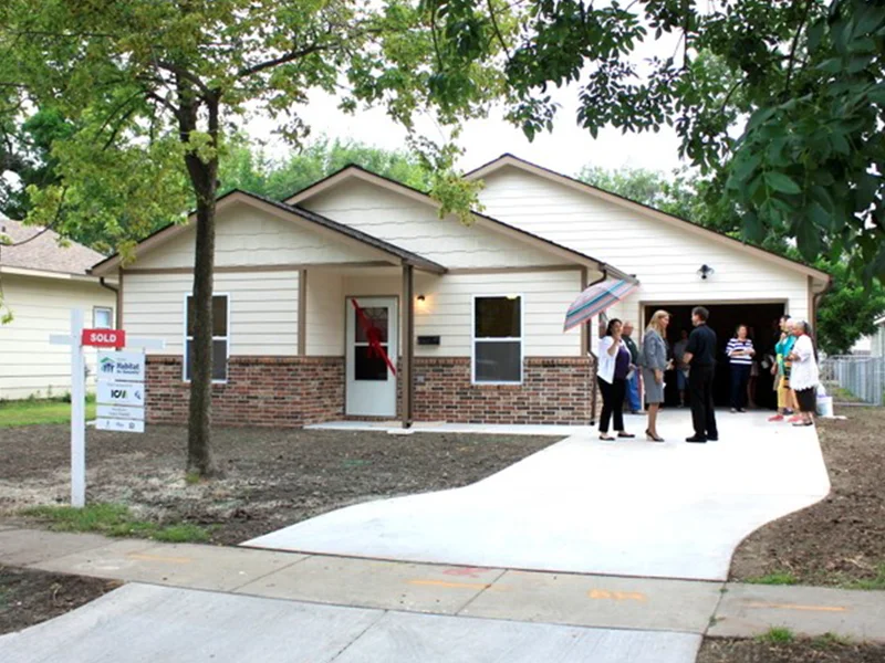 A small, single-story white house with a garage.