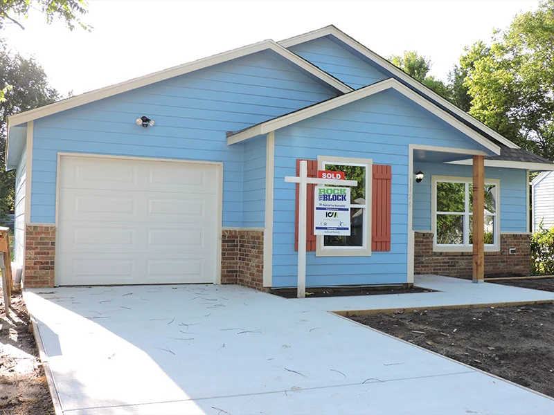 A small, single-story blue house with a garage.