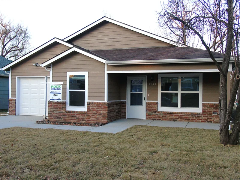 A small, single-story brown house with a garage.