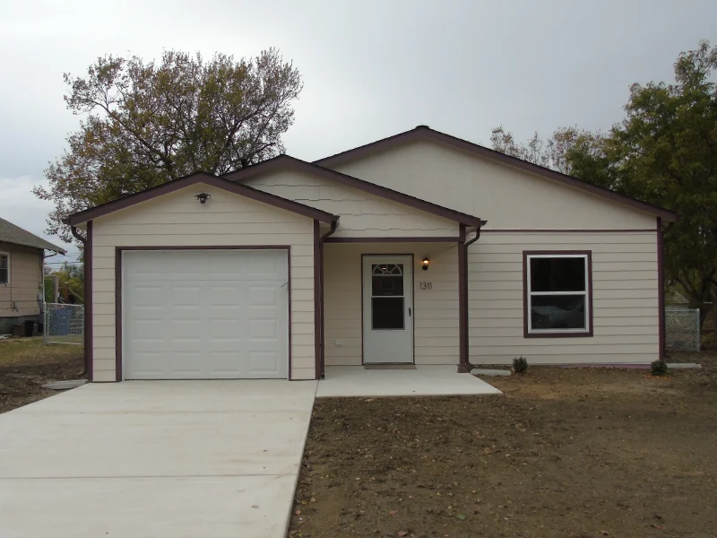 A small, single-story white house with a garage.