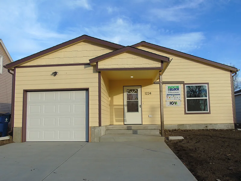 A small, single-story yellow house with a garage.