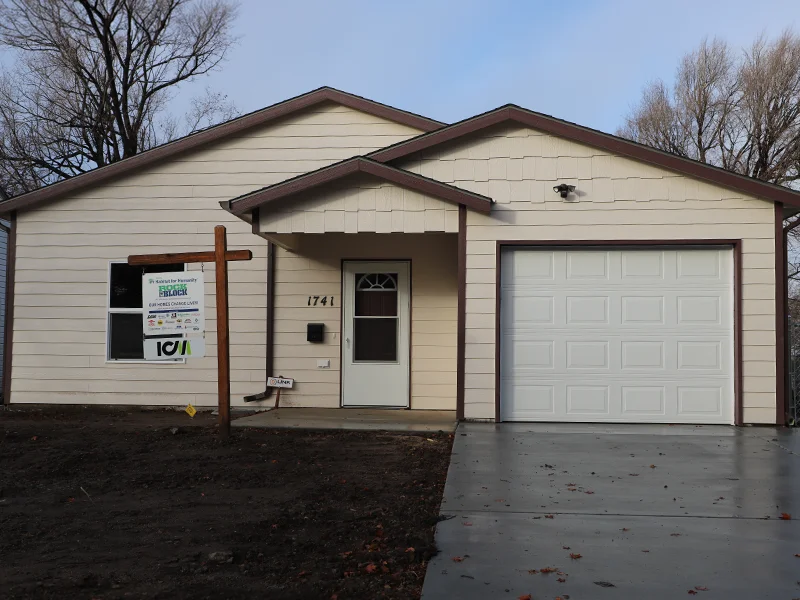 A small, single-story yellow house with a garage.
