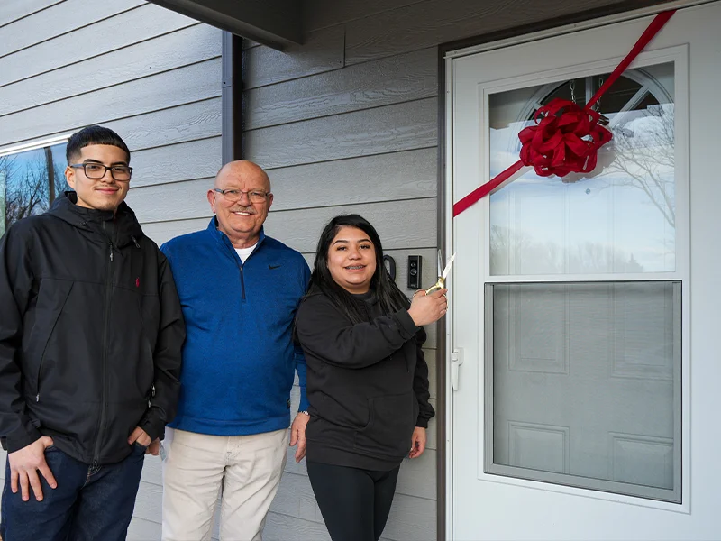 Dave VanderGriend and a couple standing in front of a door with a ribbon.