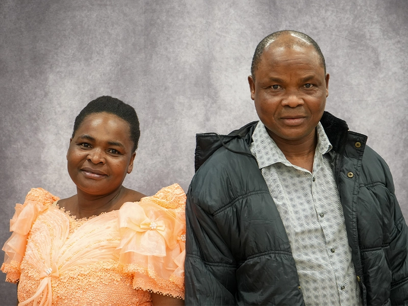 Family partners Amani and Furaha standing in front of a gray background.