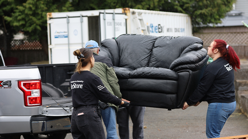 Volunteers carrying a sofa off a truck.