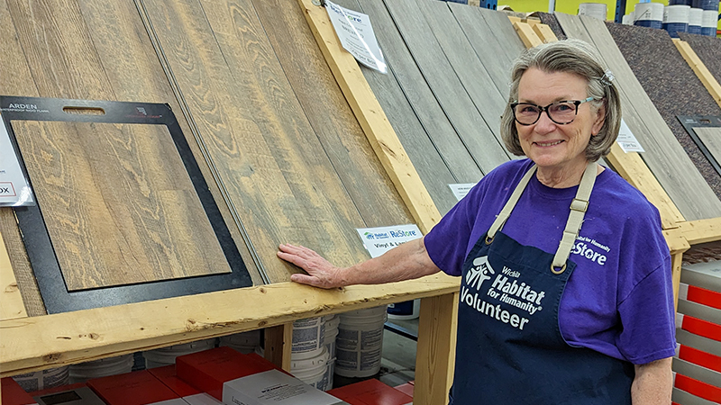 Core volunteer Connie Jason posing in front of the flooring material section.
