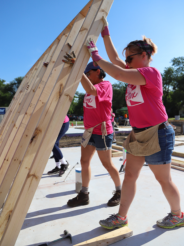 Volunteers of the Women Build are raising walls of a home.