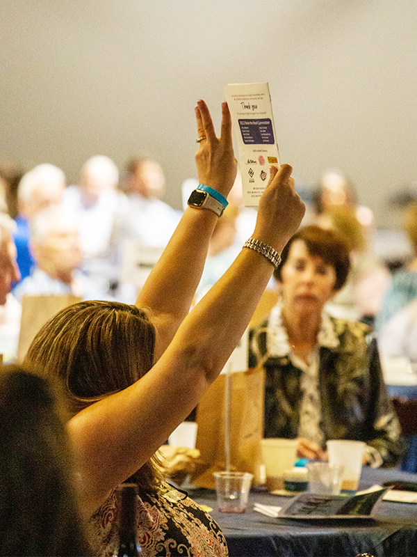 A past participant raising her card during a live auction.