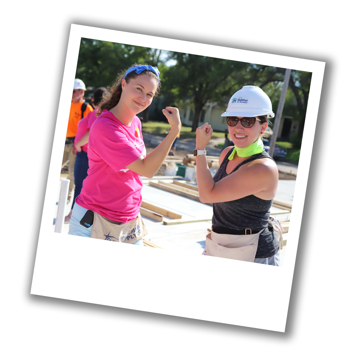 Two women flexing their arms at a Women Build event.
