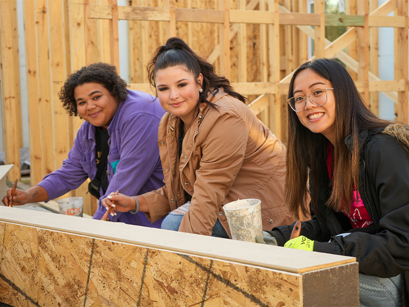 Three volunteers enjoying painting at a construction site.