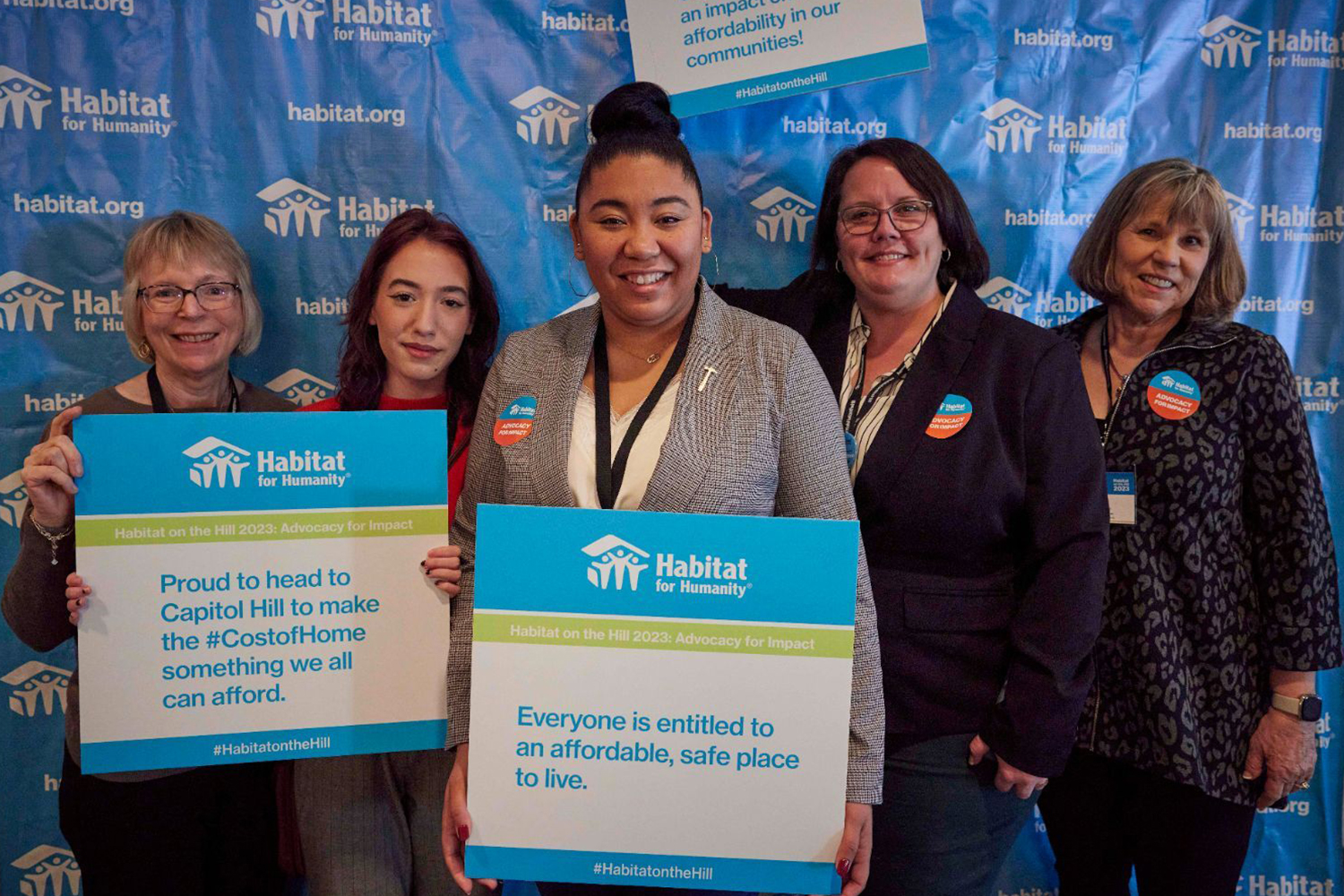 Habitat staff and volunteers holding Cost of Homes campaign signs.